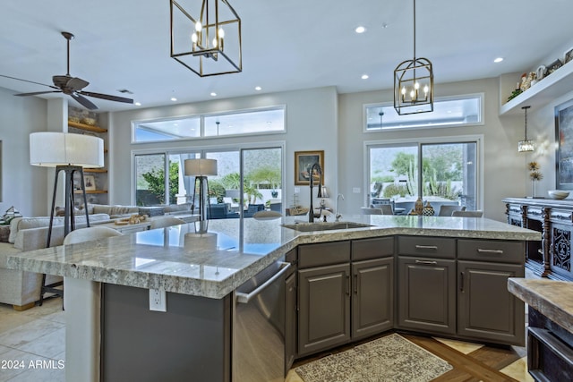 kitchen featuring ceiling fan with notable chandelier, sink, a wealth of natural light, and an island with sink