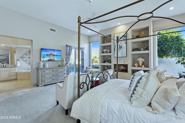 bedroom with multiple windows, ensuite bathroom, light tile patterned flooring, and a tiled fireplace