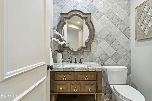 bathroom with decorative backsplash, vanity, tile walls, and toilet