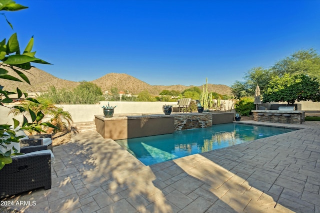 view of pool with a mountain view, an outdoor kitchen, and a patio area