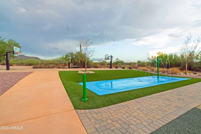 view of sport court featuring a lawn and a mountain view