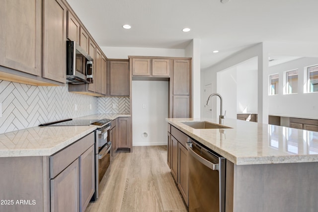 4053 Desert Moon Dr, Wickenburg, AZ 85390 - kitchen featuring stainless steel appliances, an island with sink, light wood-style floors, backsplash, and recessed lighting