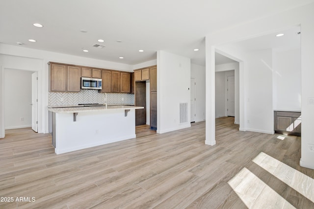 4053 Desert Moon Dr, Wickenburg, AZ 85390 - kitchen with stainless steel microwave, recessed lighting, light countertops, a center island with sink, and decorative backsplash