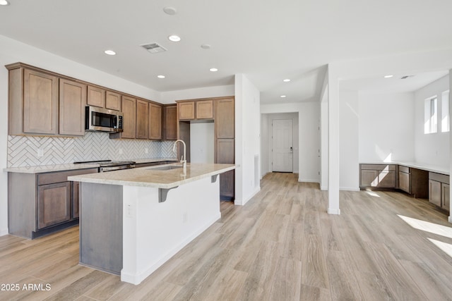 4053 Desert Moon Dr, Wickenburg, AZ 85390 - kitchen featuring stainless steel microwave, light wood-style flooring, light countertops, tasteful backsplash, and recessed lighting
