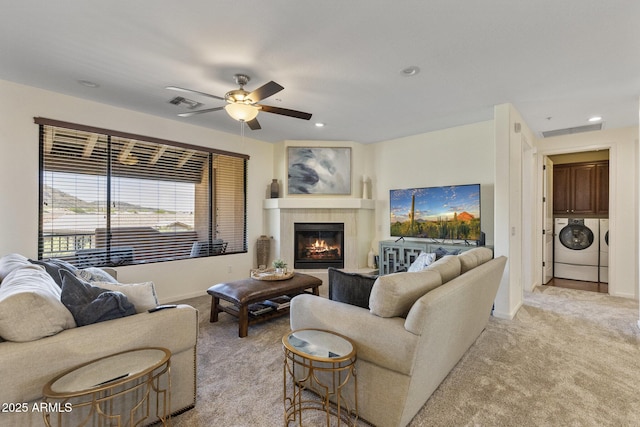living room with baseboards, ceiling fan, light carpet, and washing machine and clothes dryer
