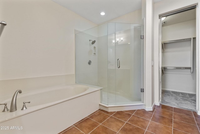 bathroom featuring tile patterned floors, a spacious closet, a shower stall, and a bath