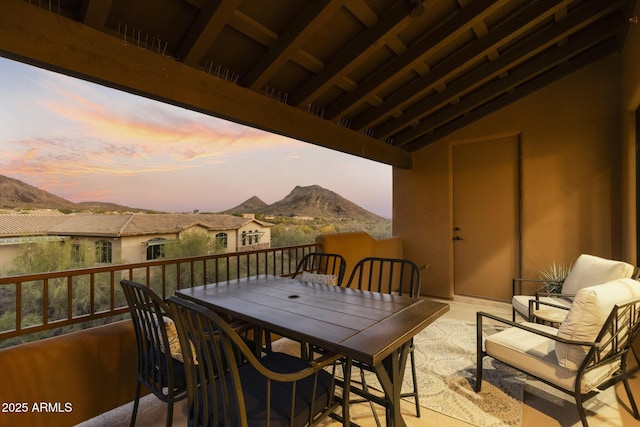 balcony at dusk with a mountain view and outdoor dining space