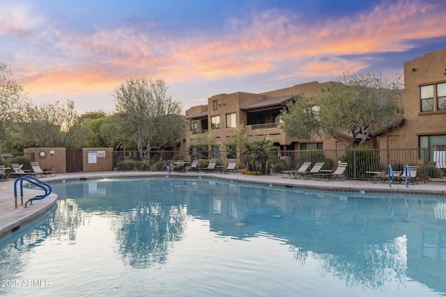 community pool with a patio area and fence