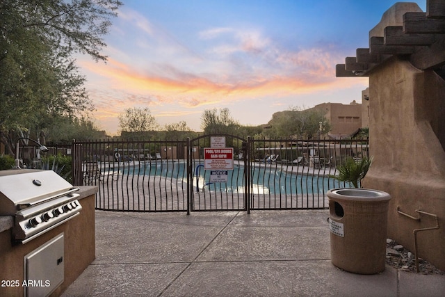 community pool with a patio, fence, and a grill