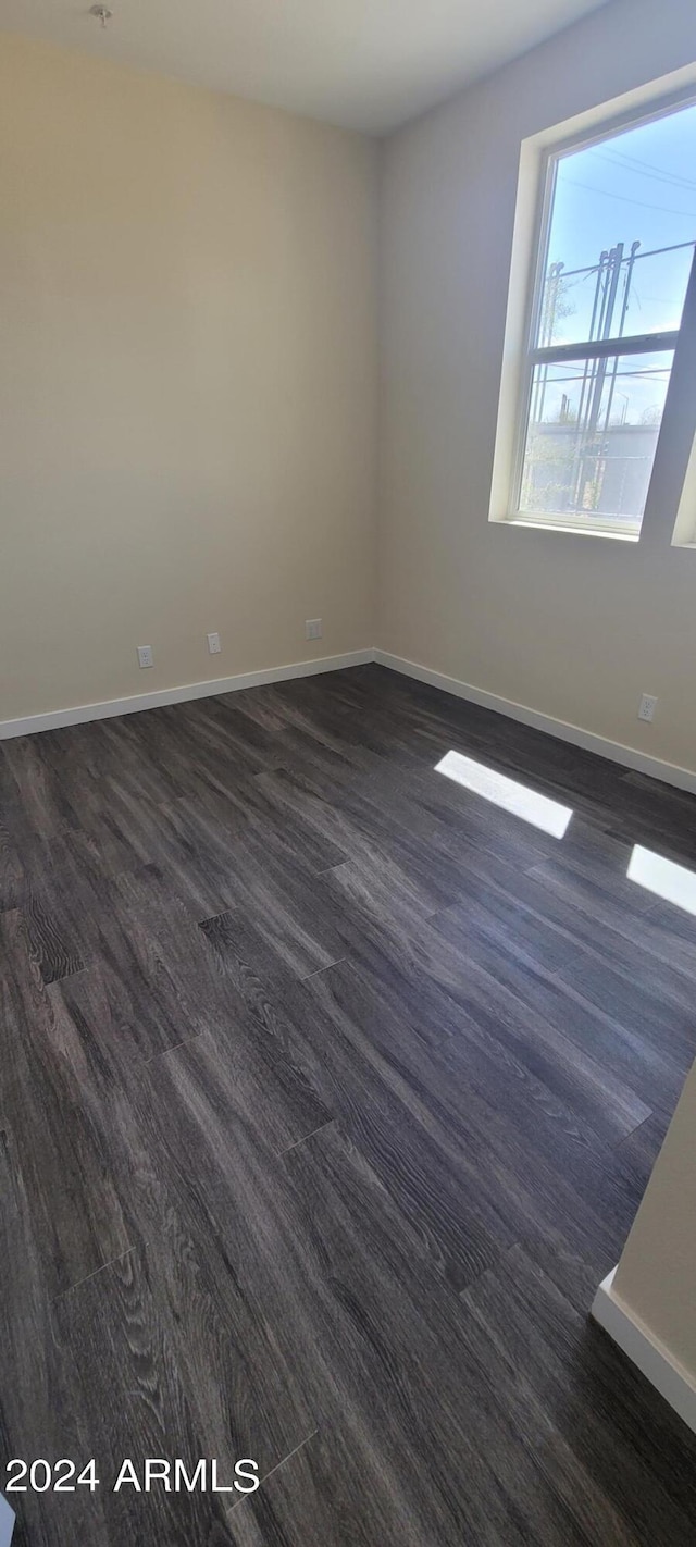 unfurnished room with dark wood-style floors and baseboards