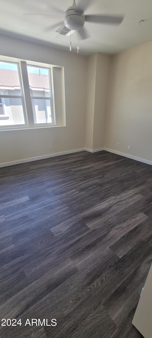 empty room with ceiling fan, dark wood-style flooring, and baseboards