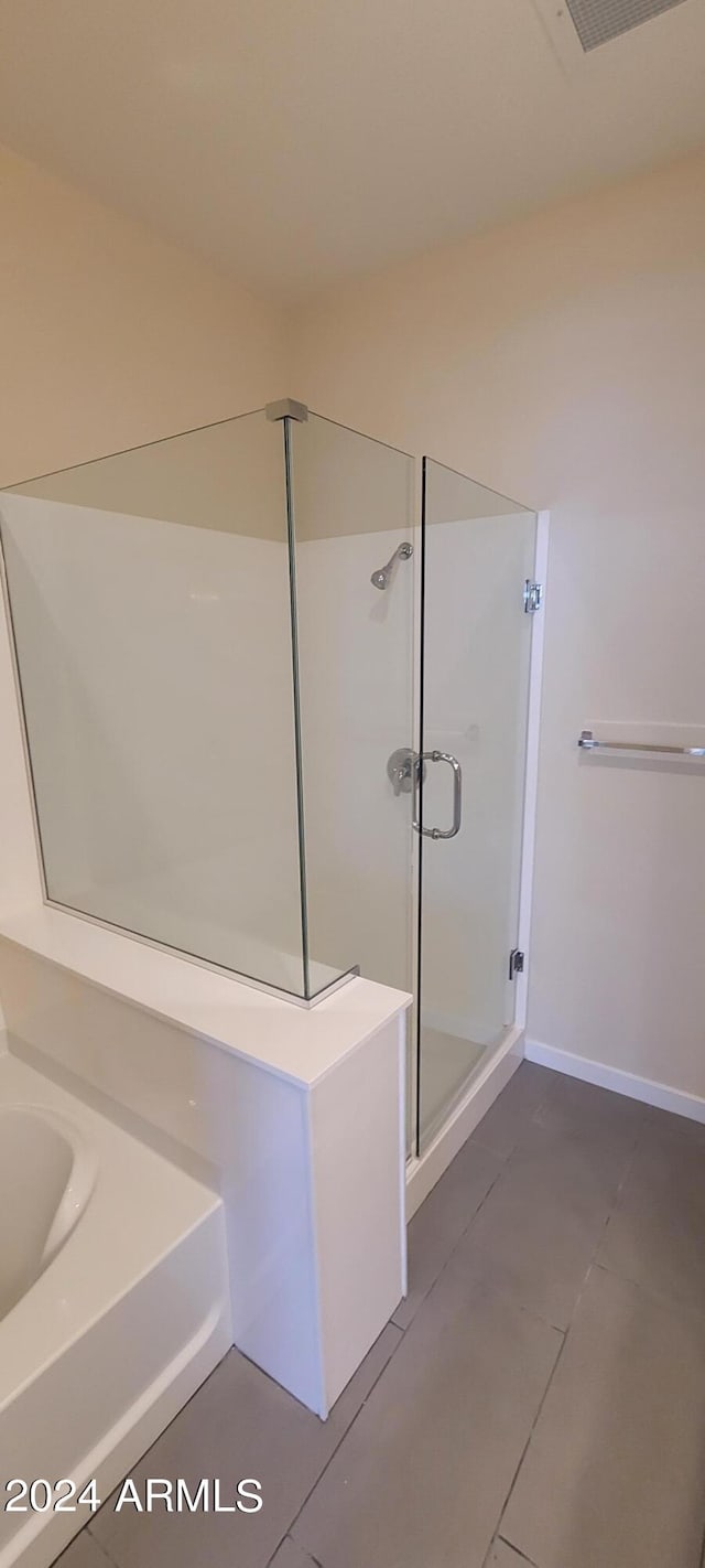 bathroom featuring tile patterned flooring, visible vents, baseboards, a shower stall, and a bath