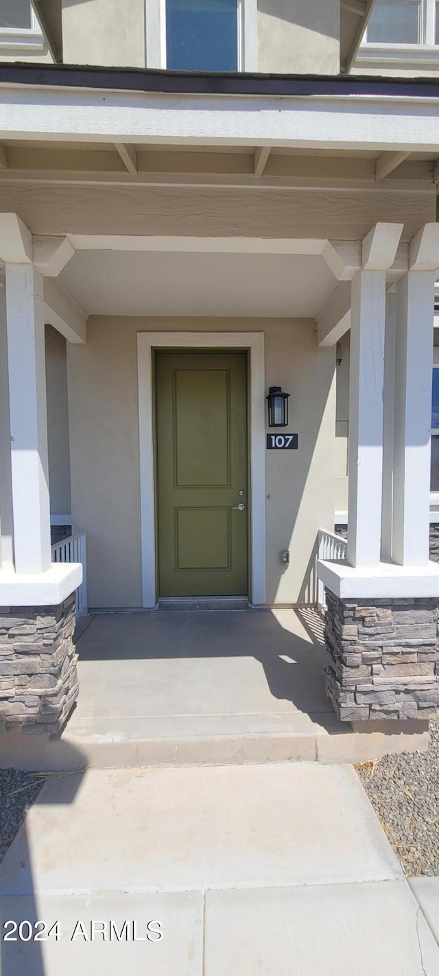 entrance to property featuring covered porch and stucco siding