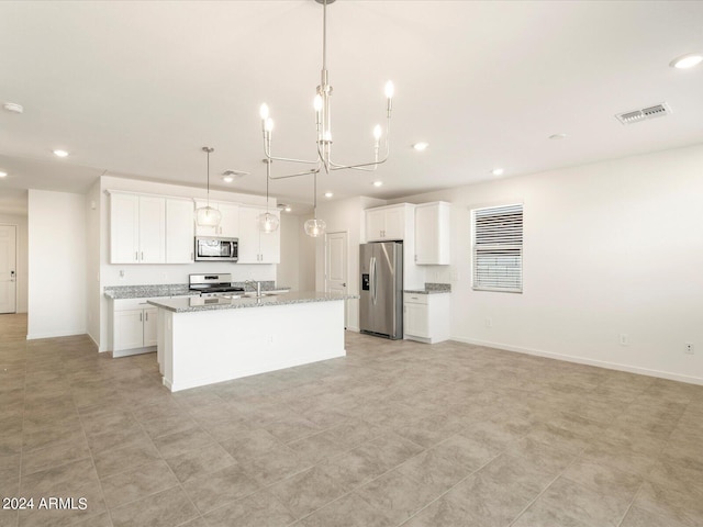 kitchen featuring white cabinets, hanging light fixtures, a center island with sink, appliances with stainless steel finishes, and light stone counters