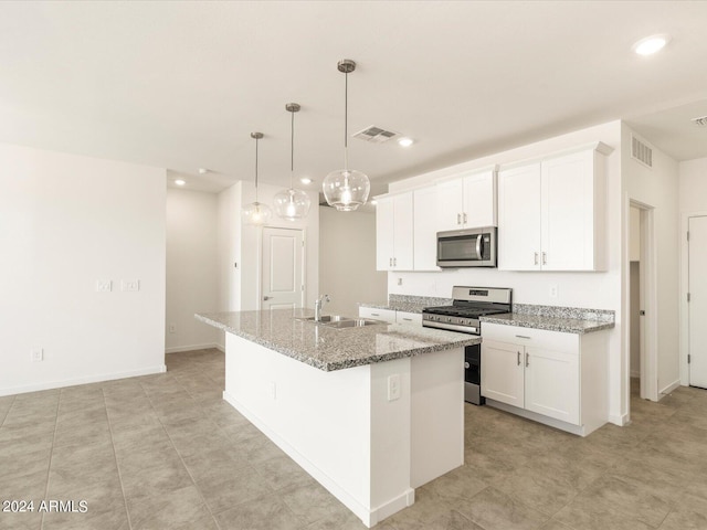 kitchen with light stone countertops, sink, white cabinetry, stainless steel appliances, and a kitchen island with sink