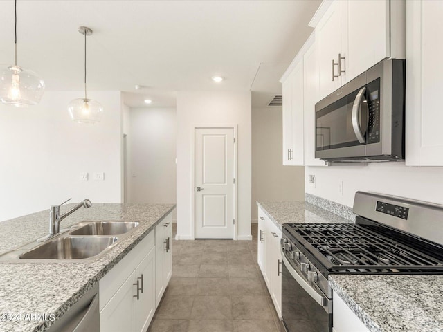 kitchen featuring white cabinets, light stone counters, appliances with stainless steel finishes, pendant lighting, and sink