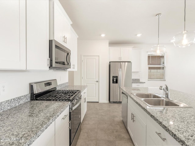 kitchen featuring light stone countertops, appliances with stainless steel finishes, sink, hanging light fixtures, and white cabinetry