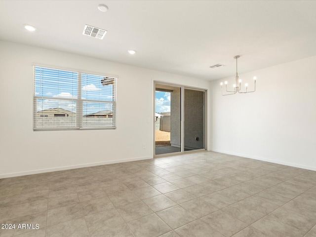 spare room with a notable chandelier and light tile patterned floors