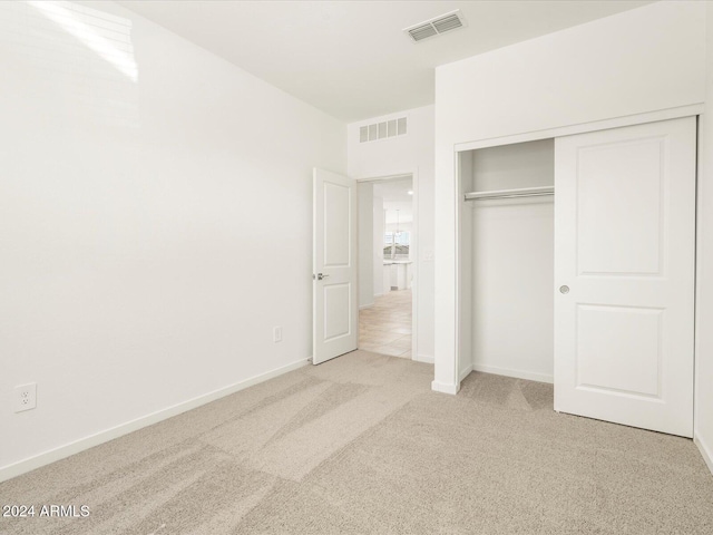 unfurnished bedroom with light carpet and a closet