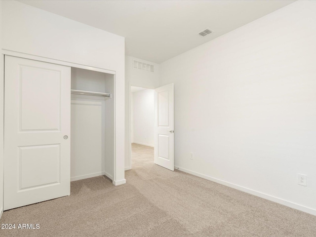 unfurnished bedroom with a closet and light carpet