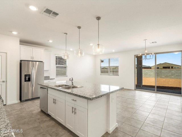 kitchen with appliances with stainless steel finishes, white cabinetry, a center island with sink, and a wealth of natural light