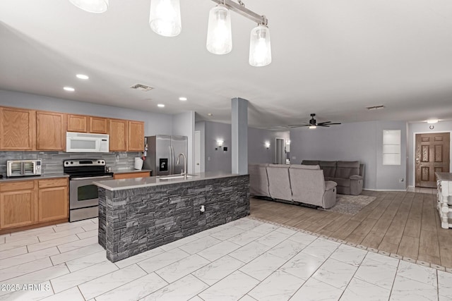 kitchen featuring open floor plan, stainless steel appliances, decorative backsplash, marble finish floor, and a kitchen island with sink
