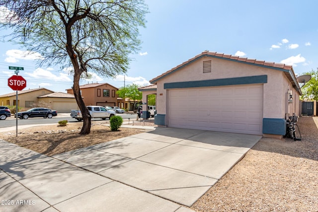 view of front of house with stucco siding, an attached garage, a tile roof, and driveway