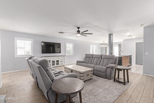 living room with a ceiling fan, baseboards, and light wood finished floors
