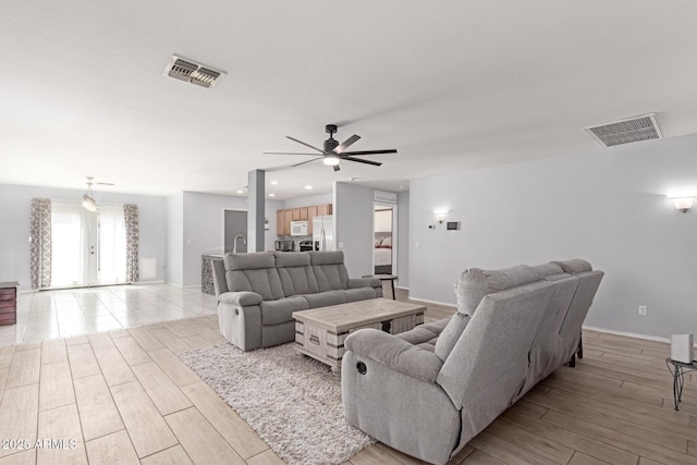 living area with visible vents, french doors, a ceiling fan, and light wood finished floors