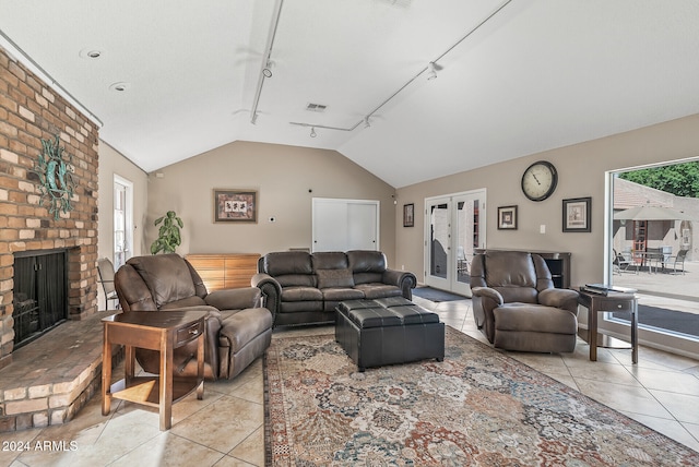 tiled living room with french doors, track lighting, a brick fireplace, and vaulted ceiling