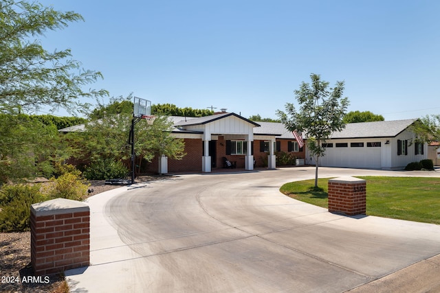 view of front facade featuring driveway, an attached garage, a front lawn, board and batten siding, and brick siding