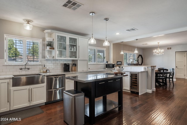 kitchen featuring visible vents, decorative backsplash, dark wood-type flooring, a peninsula, and a sink