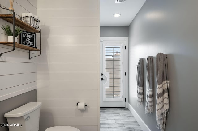 half bathroom with visible vents, wood finished floors, toilet, and baseboards