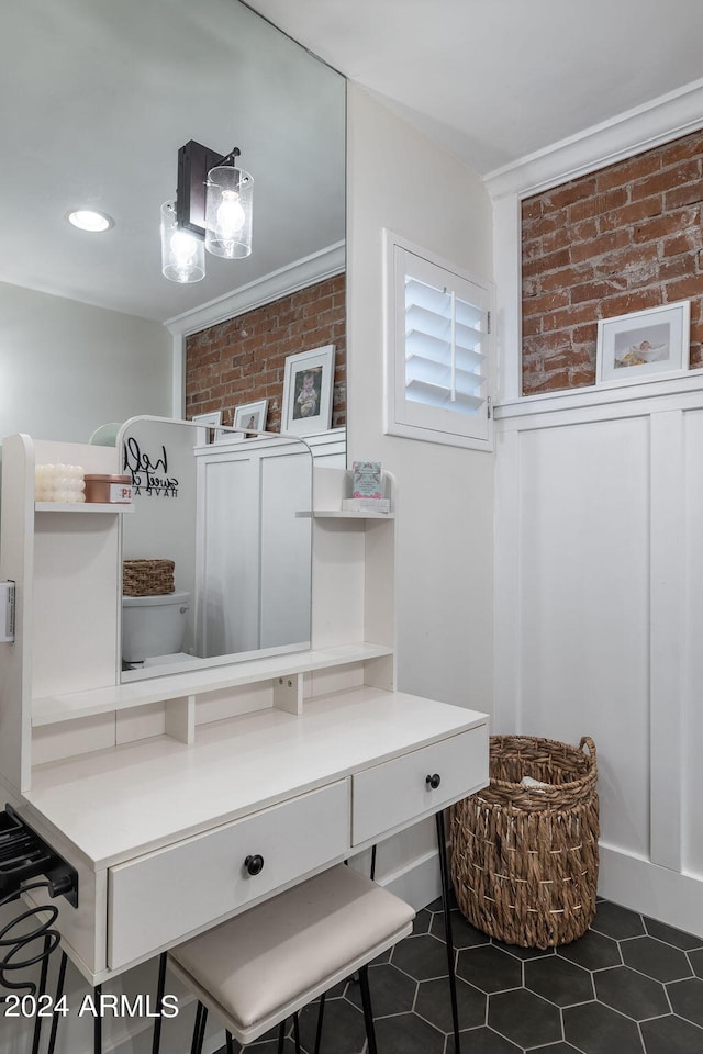 mudroom with brick wall, ornamental molding, and dark tile patterned flooring