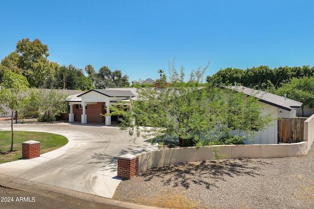 view of front facade featuring concrete driveway and fence