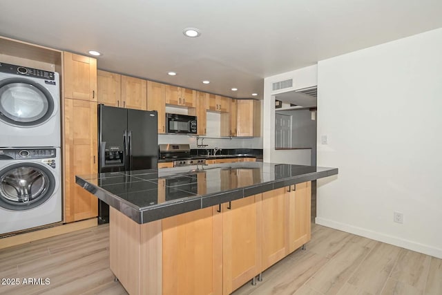 3637 E Monterosa St Unit 8, Phoenix, AZ 85018 - kitchen featuring black appliances, stacked washer and clothes dryer, light brown cabinets, light wood-style flooring, and recessed lighting