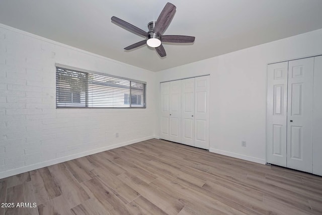 3637 E Monterosa St Unit 8, Phoenix, AZ 85018 - unfurnished bedroom with multiple closets, wood finished floors, brick wall, and ceiling fan