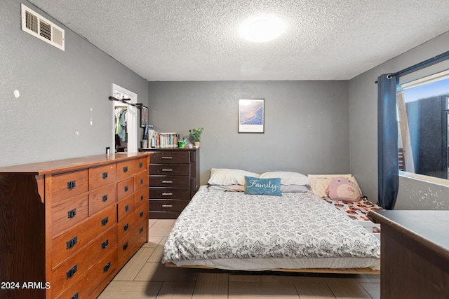 bedroom with a textured ceiling and light tile patterned floors