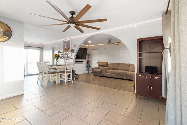 living room featuring ceiling fan, a textured ceiling, and light hardwood / wood-style floors