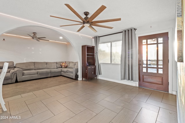 unfurnished living room featuring a textured ceiling, wood-type flooring, and ceiling fan