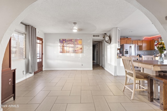 unfurnished dining area featuring ceiling fan and a textured ceiling