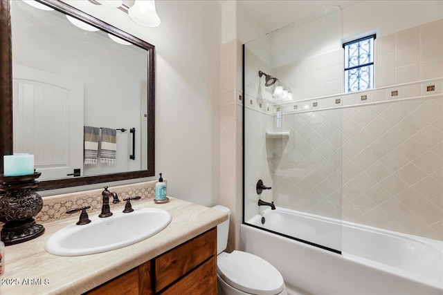 full bathroom featuring tiled shower / bath, vanity, and toilet