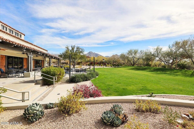 view of yard featuring ceiling fan, a mountain view, and a patio