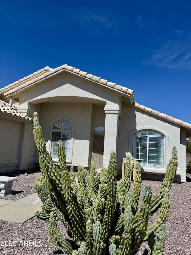 view of property exterior with stucco siding and a tiled roof