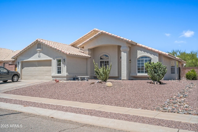 mediterranean / spanish-style home with a garage, stucco siding, driveway, and a tile roof