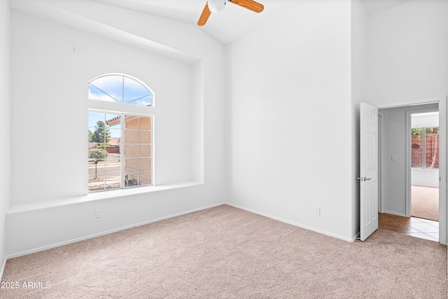 carpeted empty room featuring baseboards, a ceiling fan, and lofted ceiling