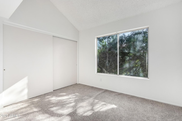 unfurnished room featuring a textured ceiling, carpet floors, and vaulted ceiling