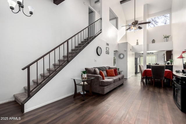 living room with ceiling fan with notable chandelier, a towering ceiling, and dark wood-type flooring