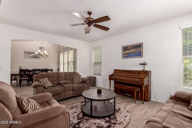 20409 W Thayer St, Buckeye, AZ 85396 - living room featuring a chandelier, light wood-style flooring, a ceiling fan, and arched walkways