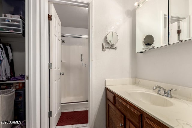 full bathroom featuring a shower stall, vanity, tile patterned flooring, and a spacious closet